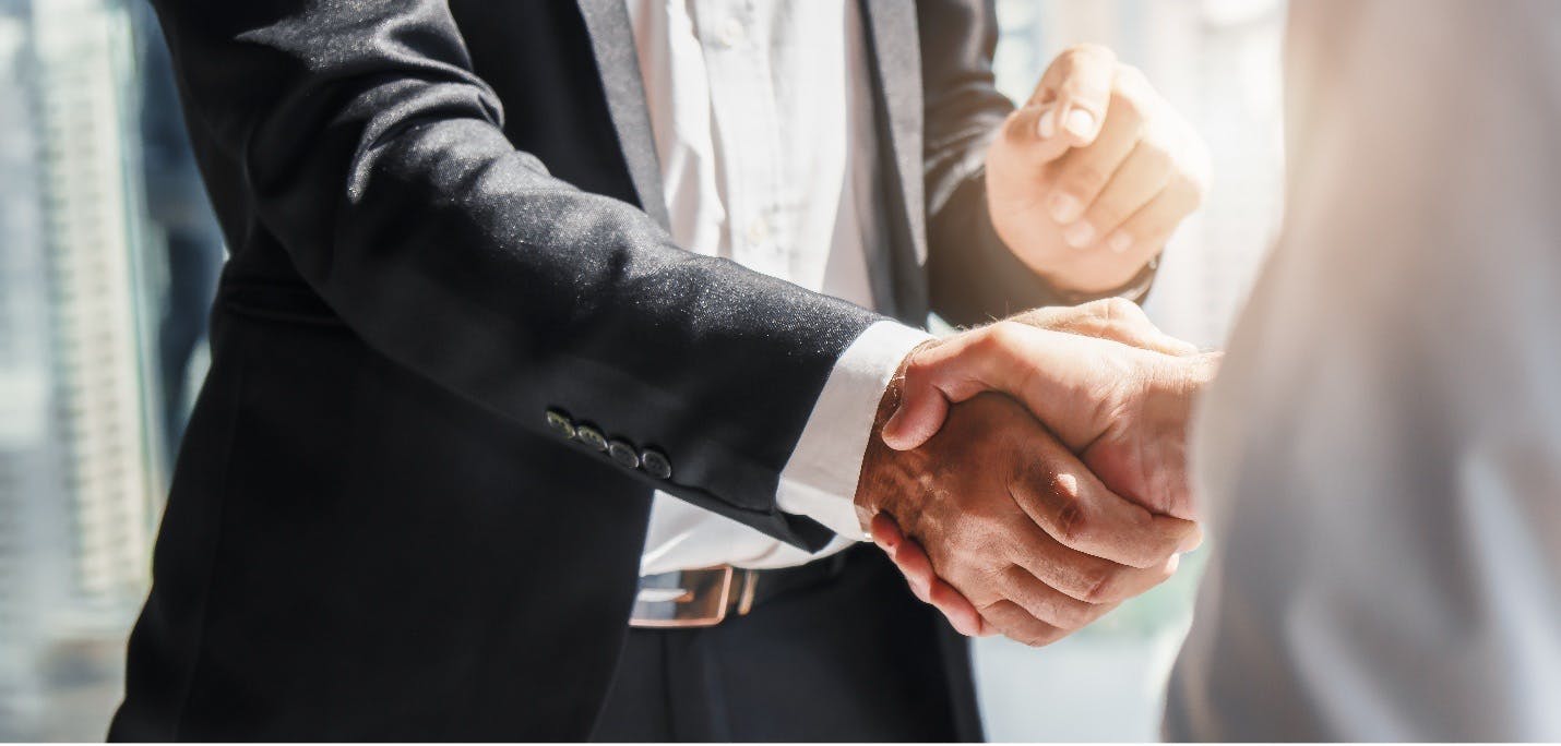 Two business professionals shaking hands over a B2B marketing deal.