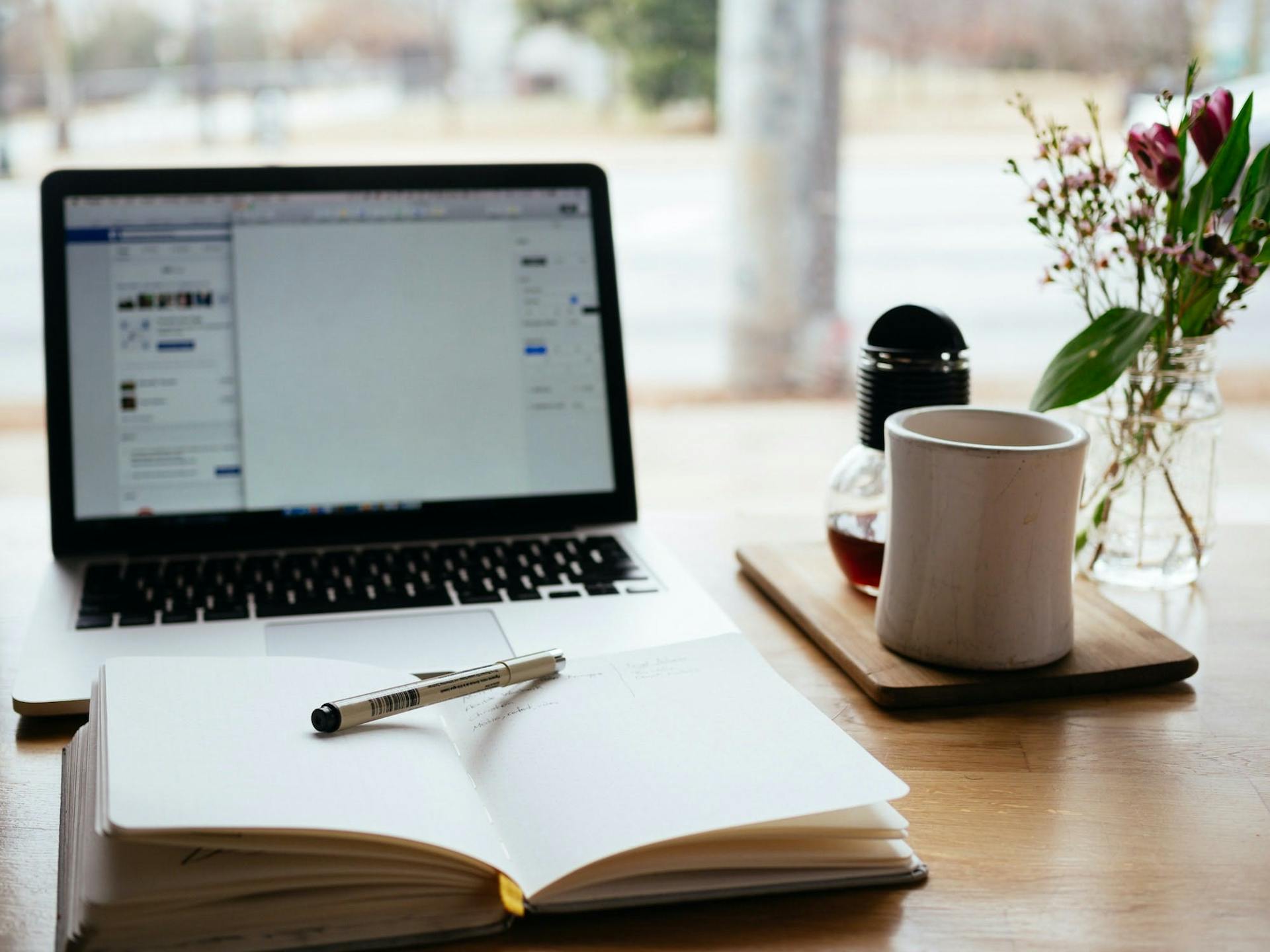 Open notebook on a desk in front of a laptop. Tips for writing the perfect press release.