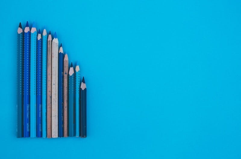 A mix of different sized pencils is laying on a blue surface