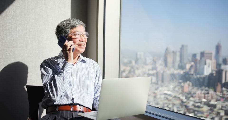 Image of Asian man on smartphone and laptop