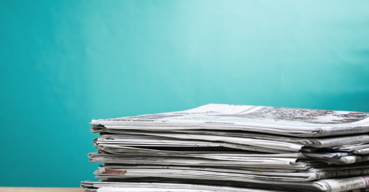 Stack of newspapers in front of a teal background