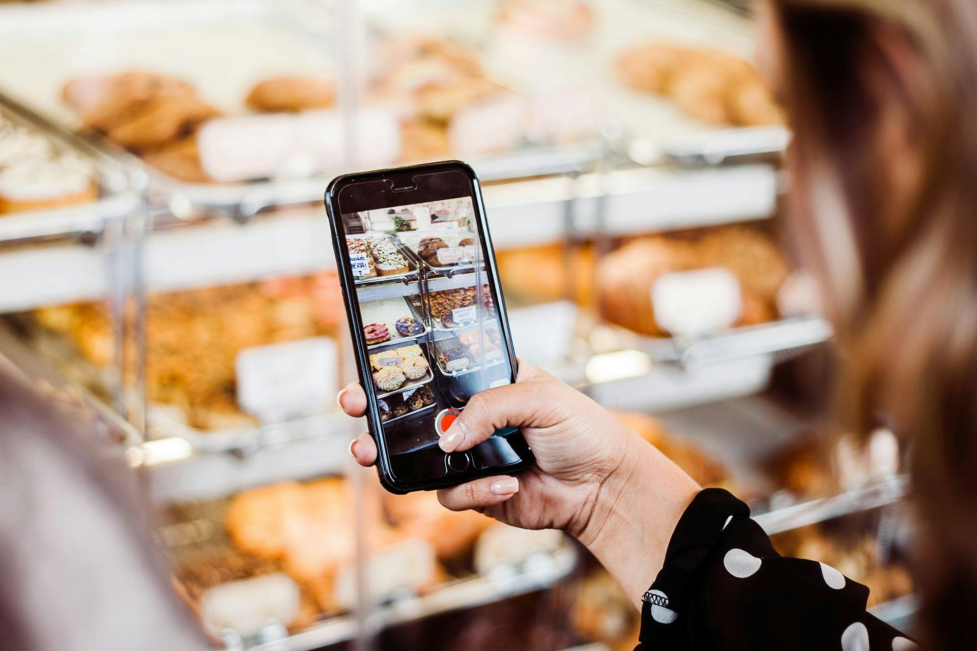 person holding a phone taking photographs of some baked treats
