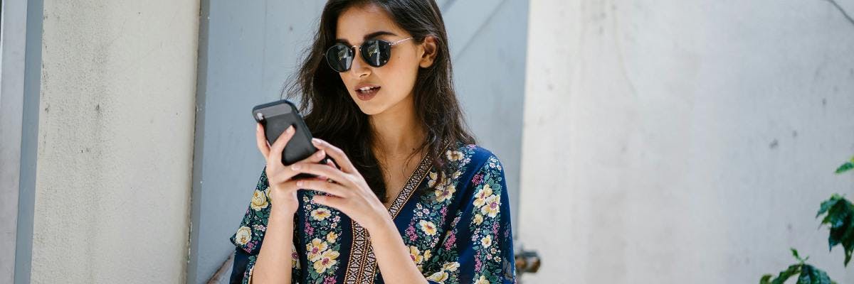 woman wearing black sunglasses and looking at her phone
