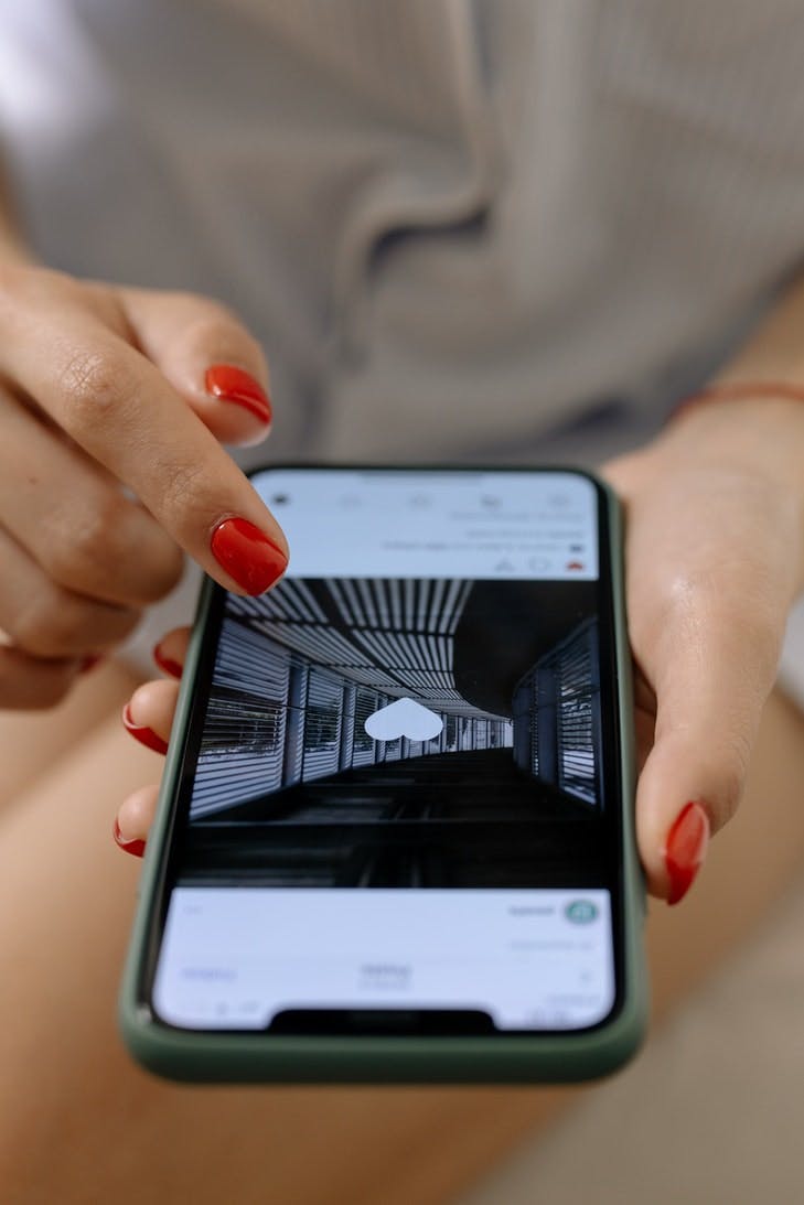 Foto eines Smartphones, das in der Hand gehalten wird. Darauf wird gerade ein Instagram Bild geliked.