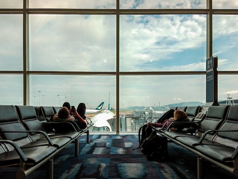  A couple is resting in an airport. In the background, you can see planes. Competitive intelligence is used in various industries such as the airline industry, tech startups, etc.
