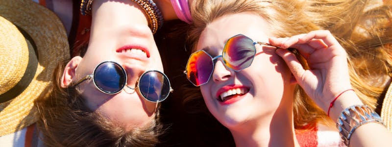 Photo of two young people lying down with their sunglasses in the sun