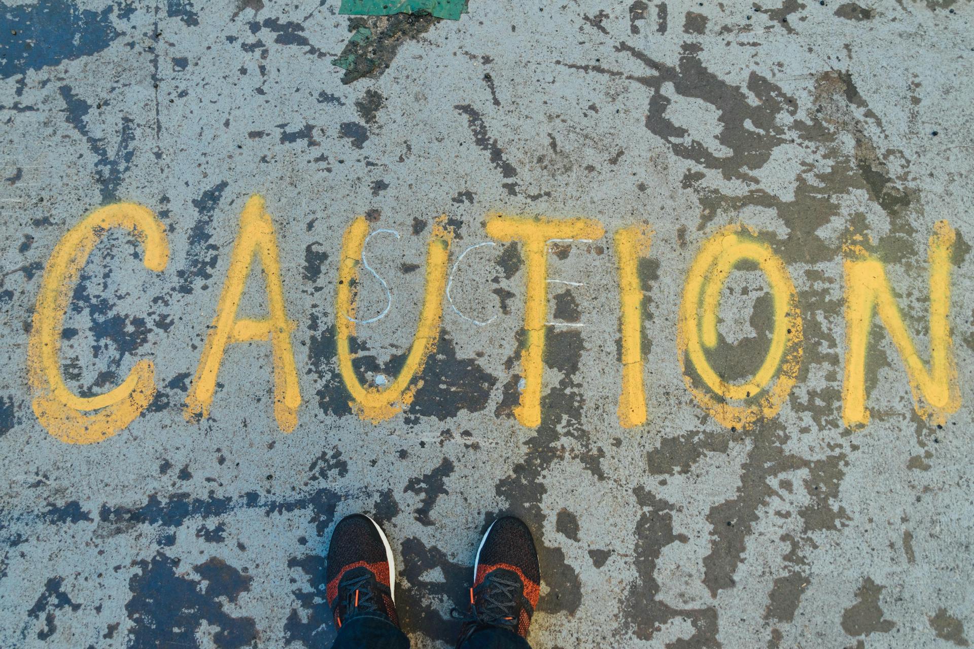 The world caution written in chalk on the ground. Avoid warnings or spammy announcements on social media 