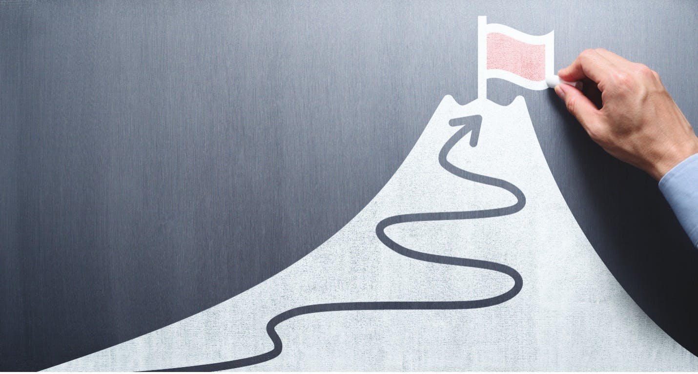 A drawing of a mountain with an arrow leading to the top where there is another drawing of a red flag that a man is holding. The image symbolizes the immensly difficult route PR teams must treavel to reacging success with their PR plans.Race up a mountain.