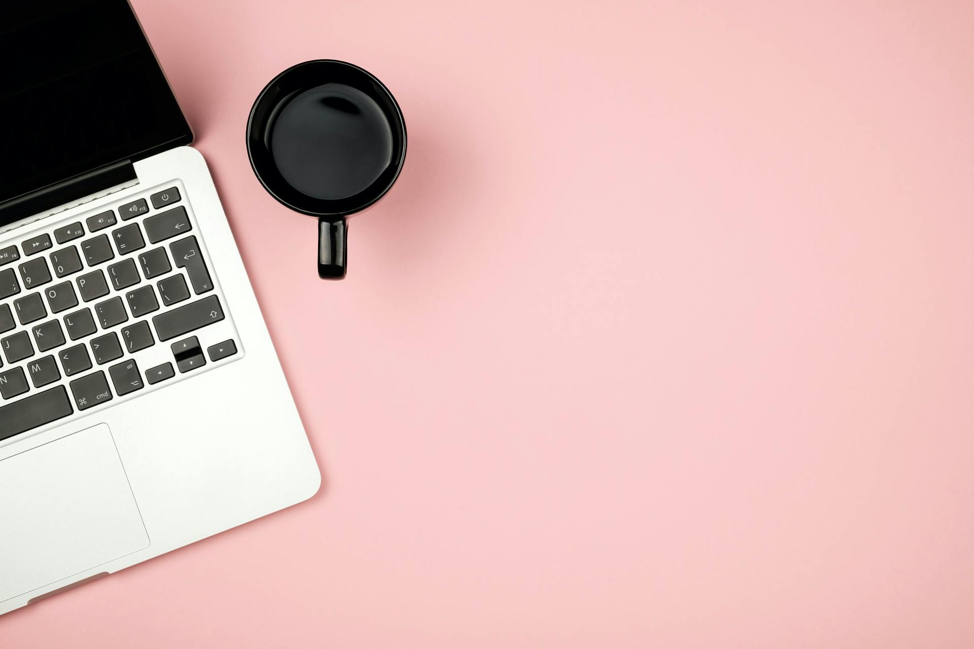 photo aérienne d'un ordinateur portable et d'une tasse à café sur une surface rose