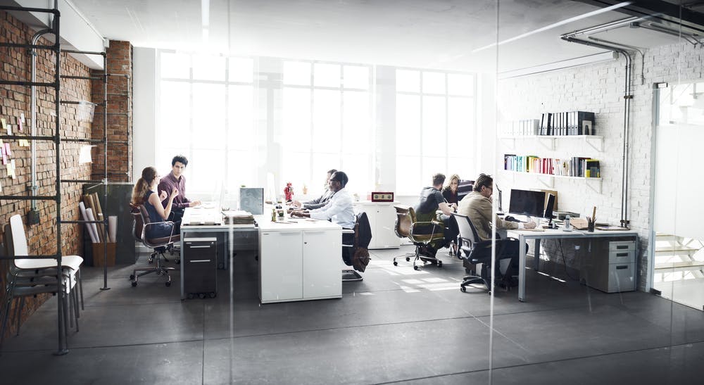 Foto Büro mit arbeitenden Menschen durch eine Glaswand fotografiert