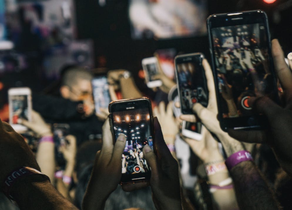 Multiple people holding up smartphones and filming short-form videos