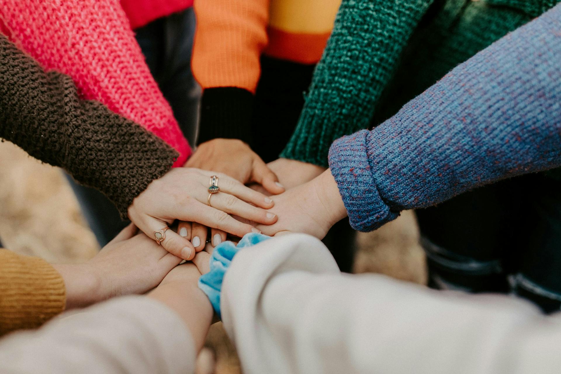 Group of diverse people extending hands to each other in a small circle. Connecting with others who have same interests is a key selling point of niche social media sites.