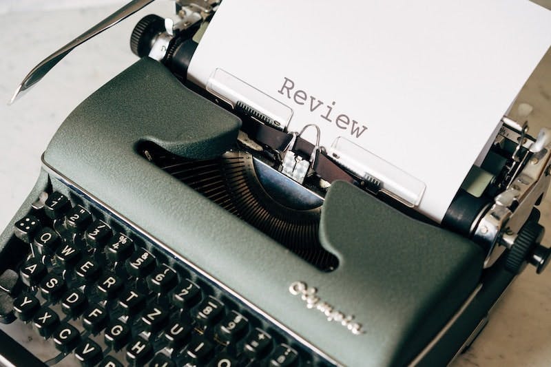 A green typewriter with a piece of paper displaying the word review