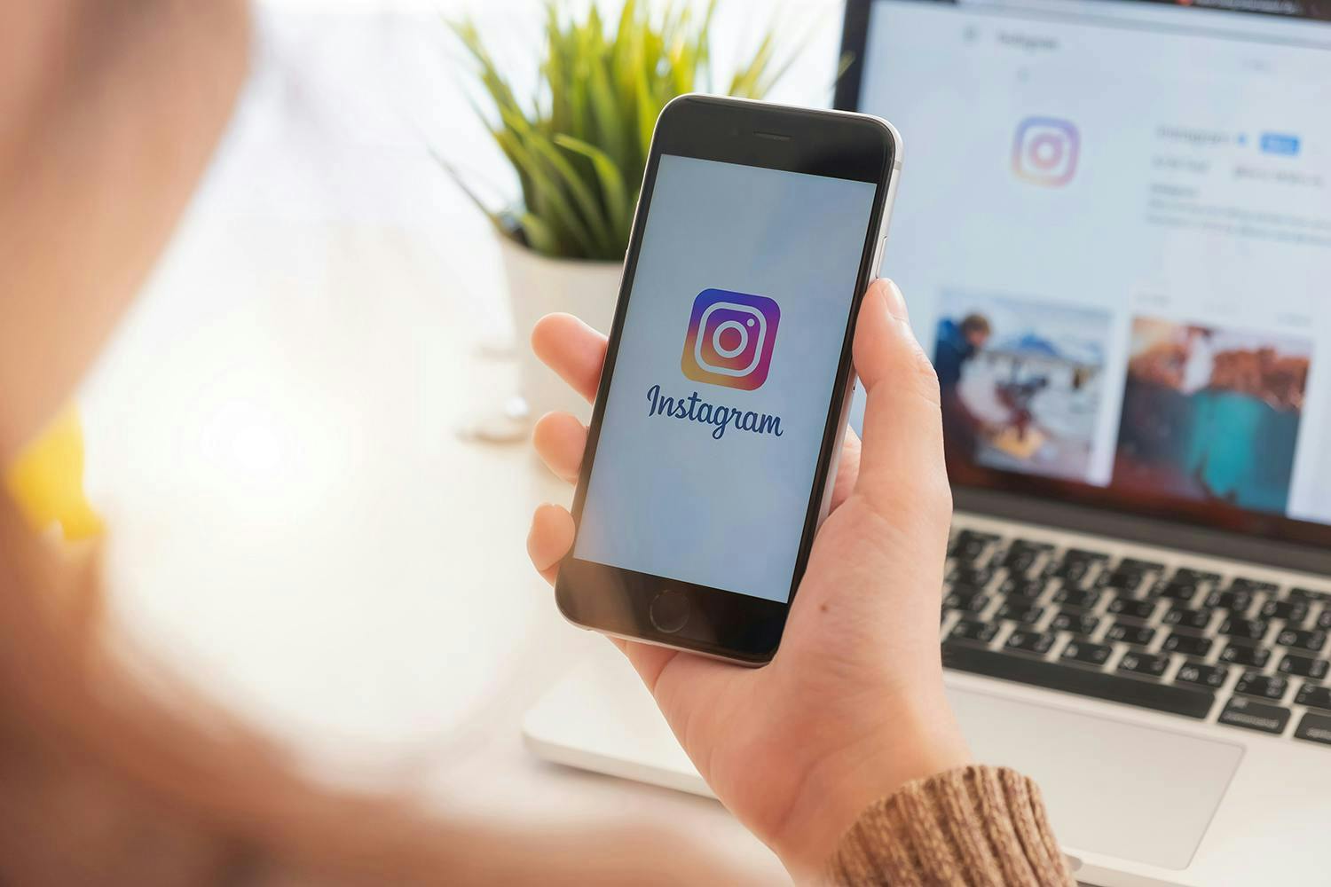 Image of the hand holding the smartphone with the Instagram logo displayed