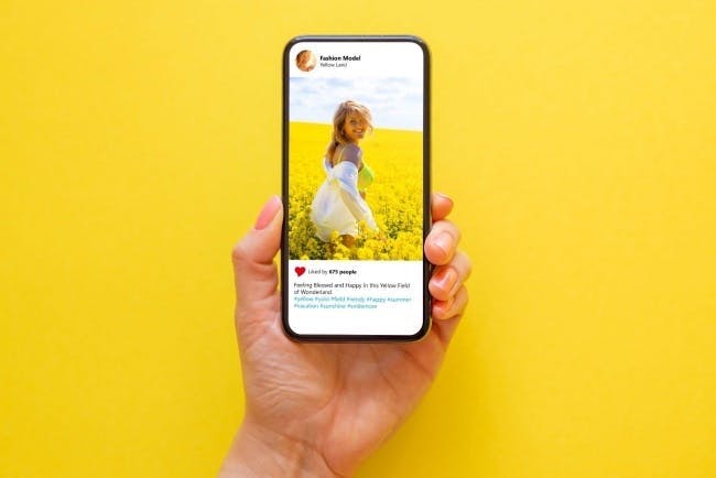 Image of a phone with an Instagram feed in front of a yellow wall