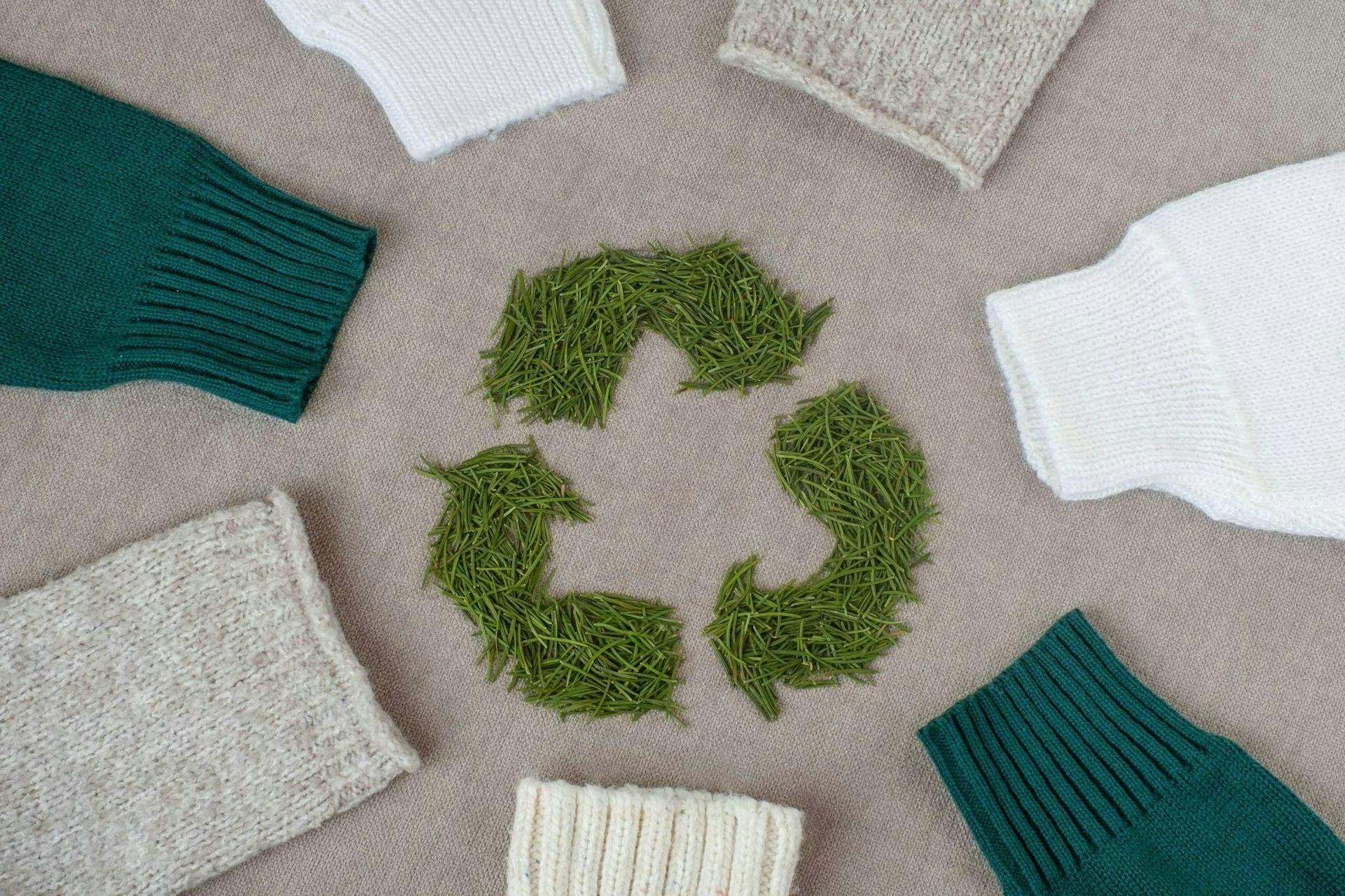 Photo of sweaters lying in a circle around the sustainability icon