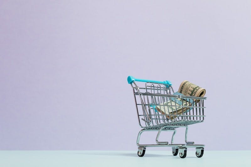 A small shopping cart with money in it