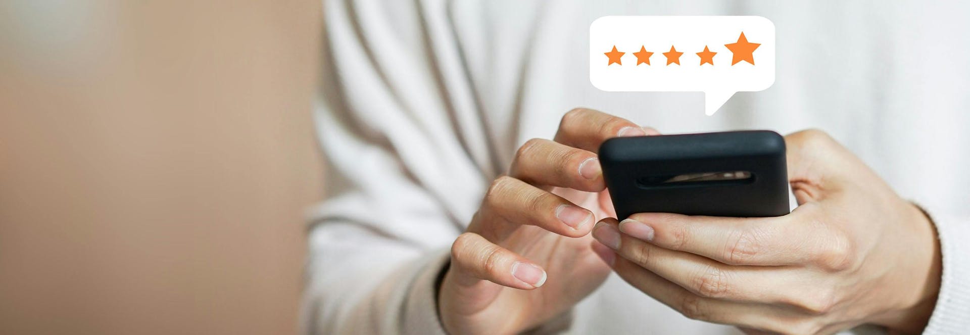 A hand playing on a phone with a speech bubble featuring 5 stars