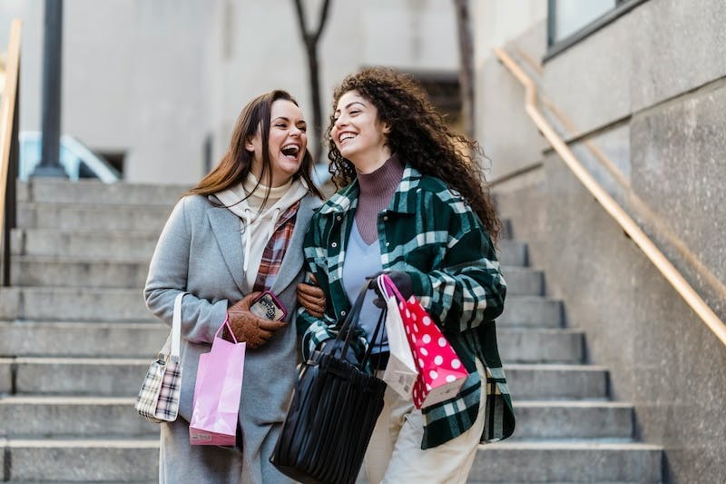 Zwei junge Frauen kommen von einem Shopping-Trip und freuen sich
