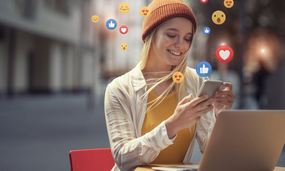 Femme qui tient son téléphone dans ses mains avec des emojis