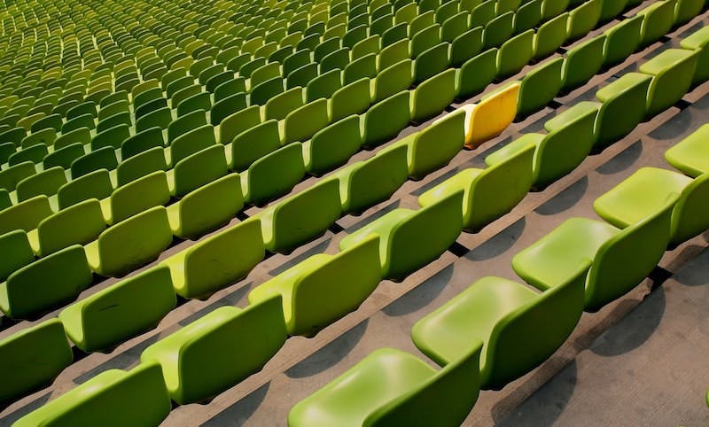 Green stadium seats, among them is a yellow one