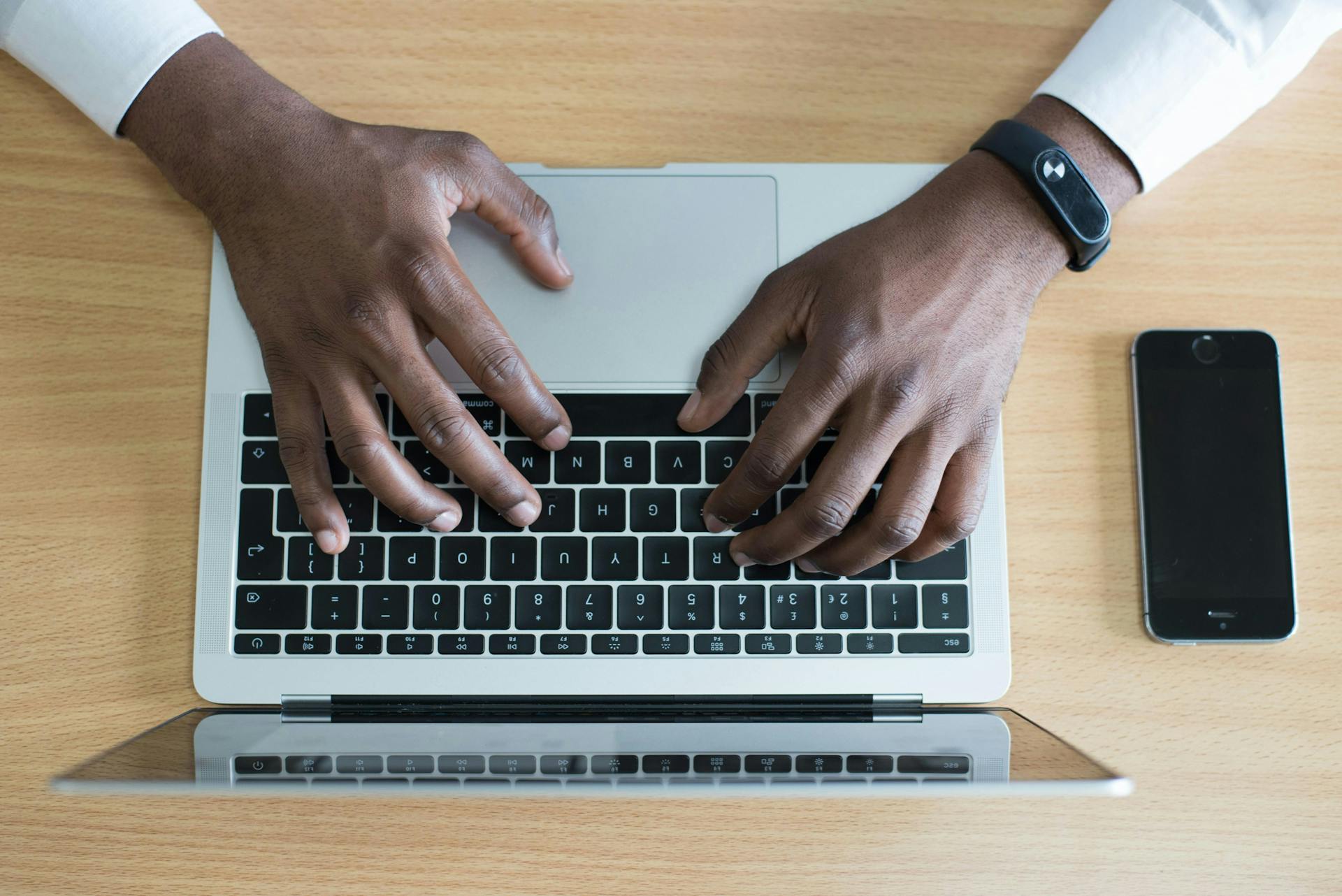 A image of a man's hands typing out an email marketing campaign on a laptop shot from above. 