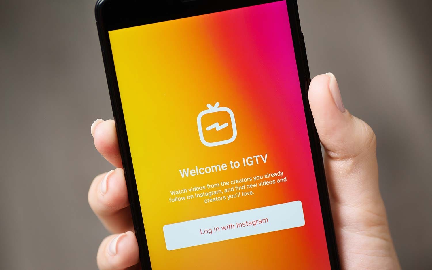 person holding mobile phone with igtv on the screen