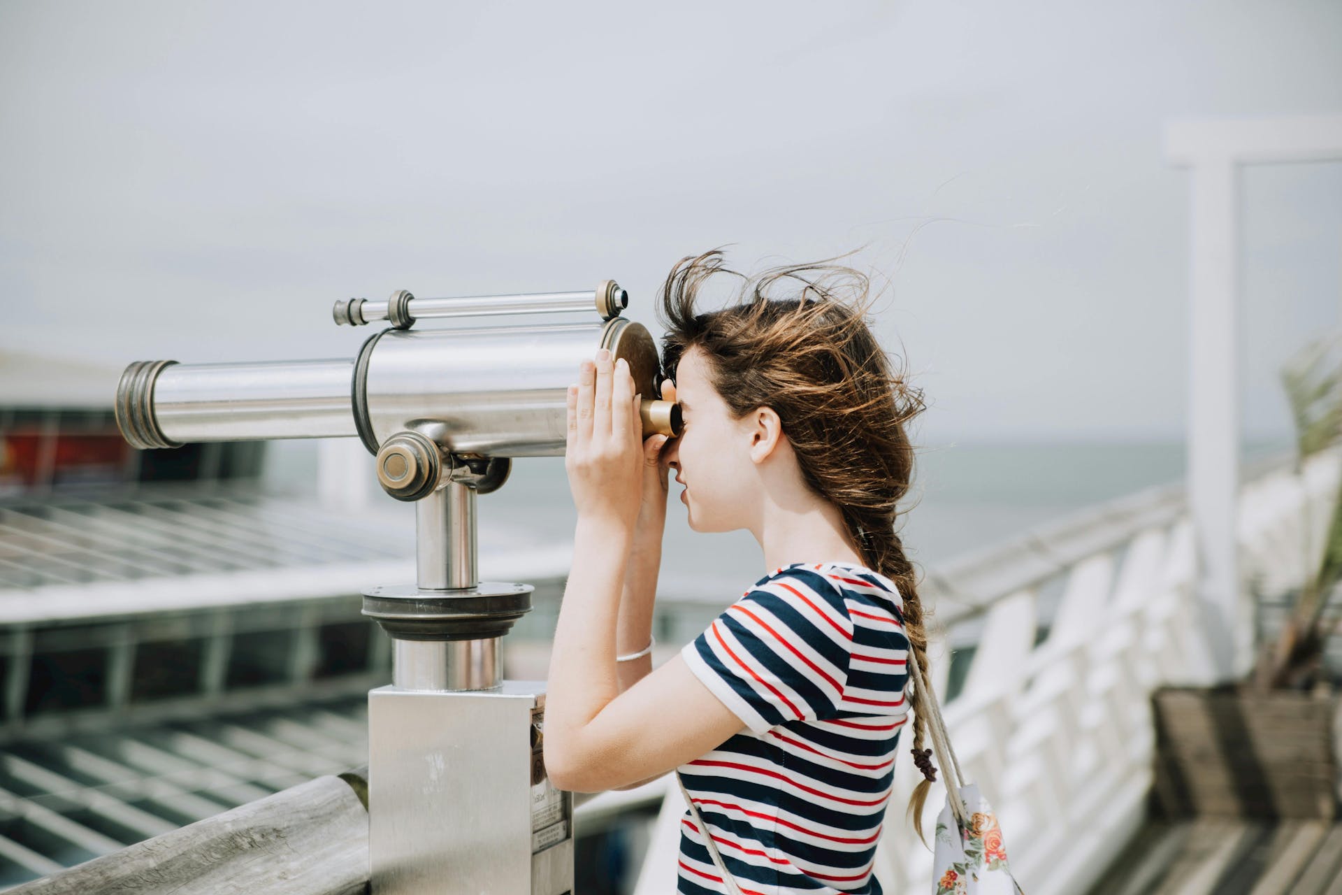 Young woman using a telescope on a pier