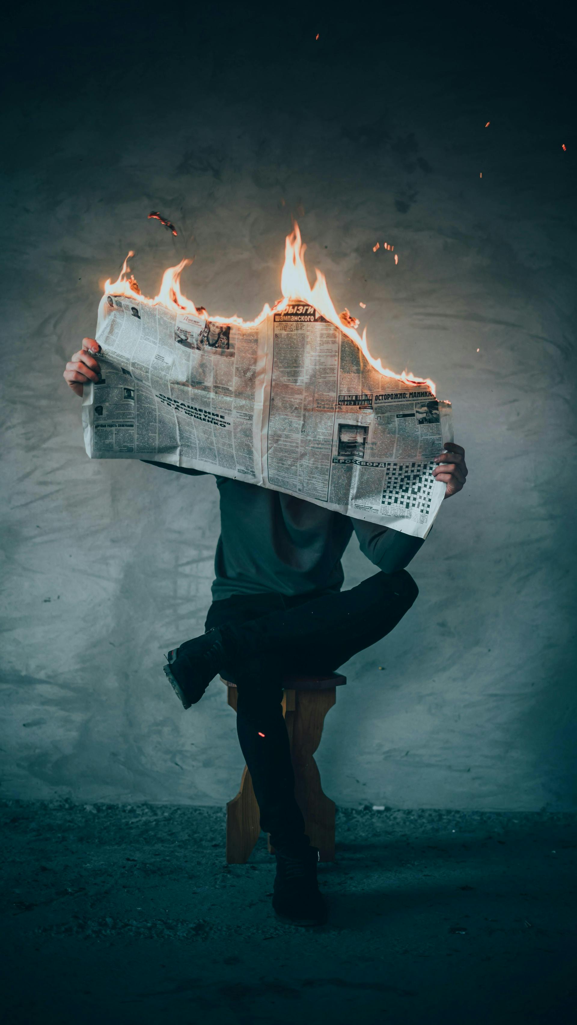 man holding a newspaper on fire