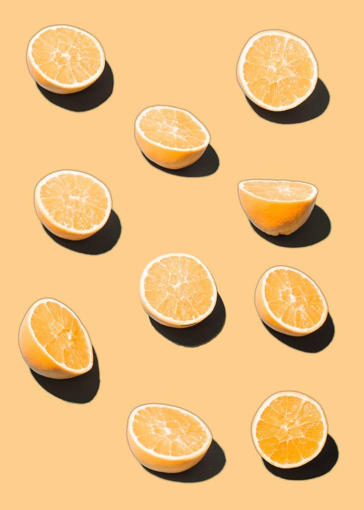 Zehn Zitronenhälften liegen auf einem gelben Hintergrund.