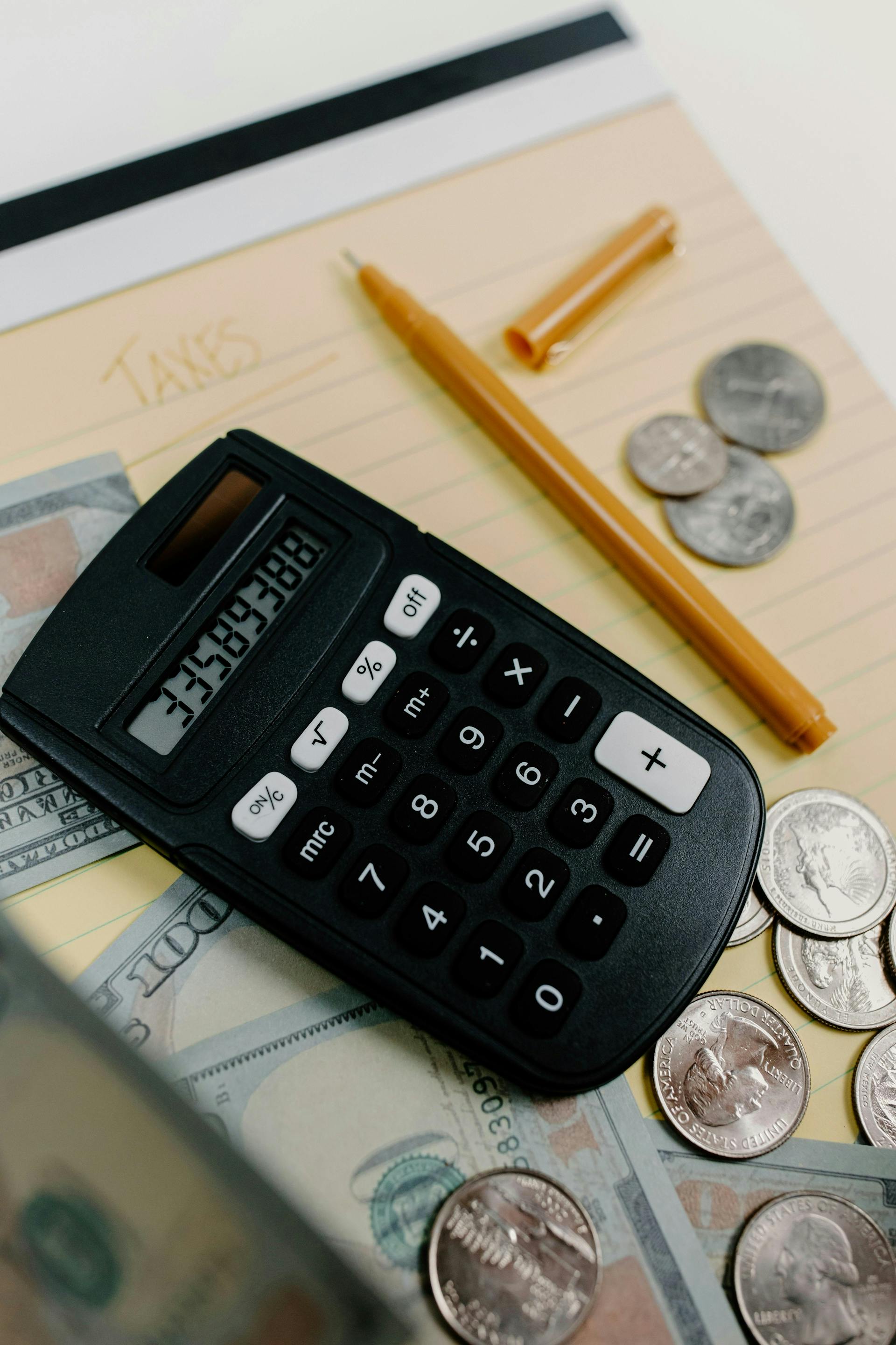Deze foto toont een rekenmachine waar geld omheen ligt. Dit alles ligt weer op een kladblok