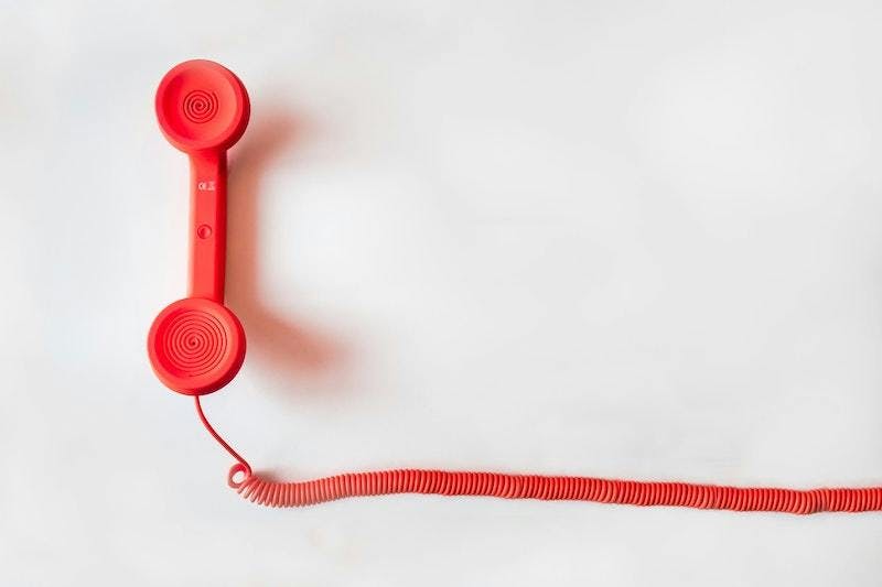 A red corded phone on a white background