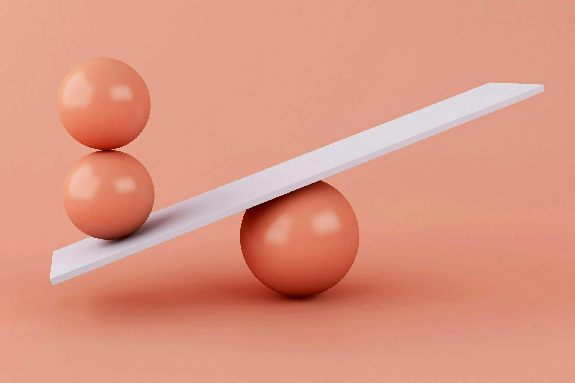 A seesaw with two orange balls balancing on one end of the seesaw. This image symbolizes the process that a marketing team may go through when weighing their different options when it comes to social media monitoring platforms.