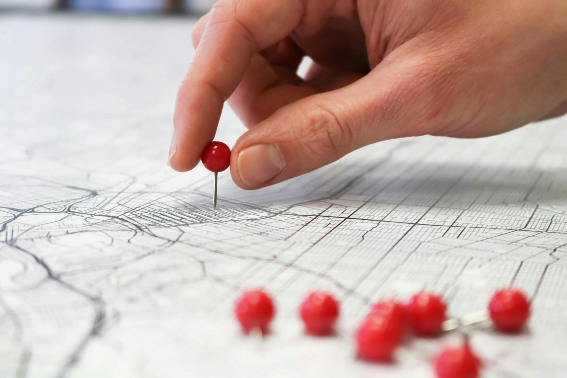Person pinning red push pin into a map, marking a specific destination on a journey. Knowing customer personalities and their purchase journey is key to content strategy  