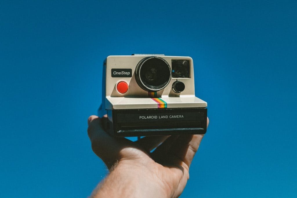 person holding a polaroid camera