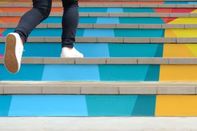Photo of someone walking up a colorful staircase