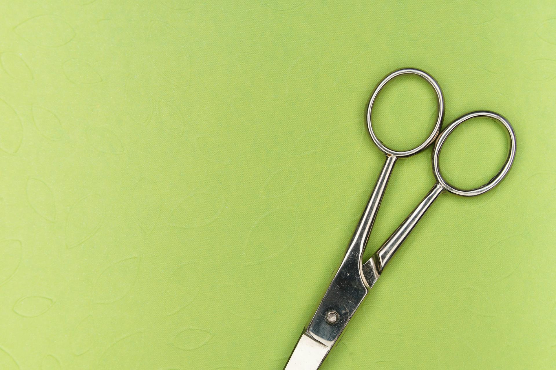 Pair of scissors on green background