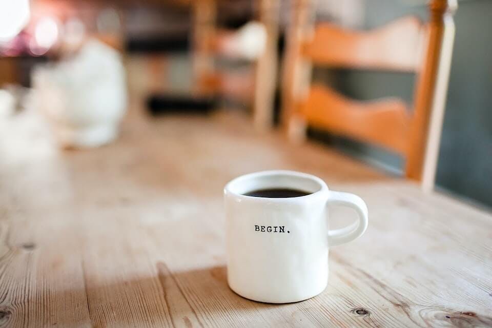 photo of a coffee mug on a table with the writing "begin"