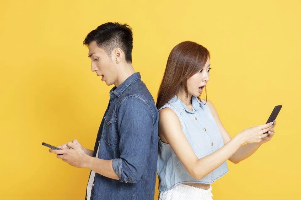 Image of two Asian mobile users checking their apps