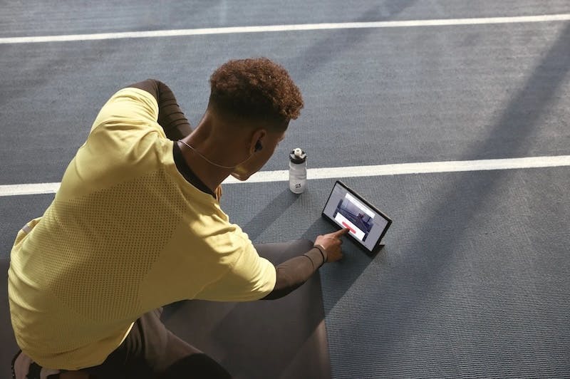 Ein junger Mann hat ein Tablet vor sich und macht einen Online-Fitnesskurs, der von Peloton angeboten wird