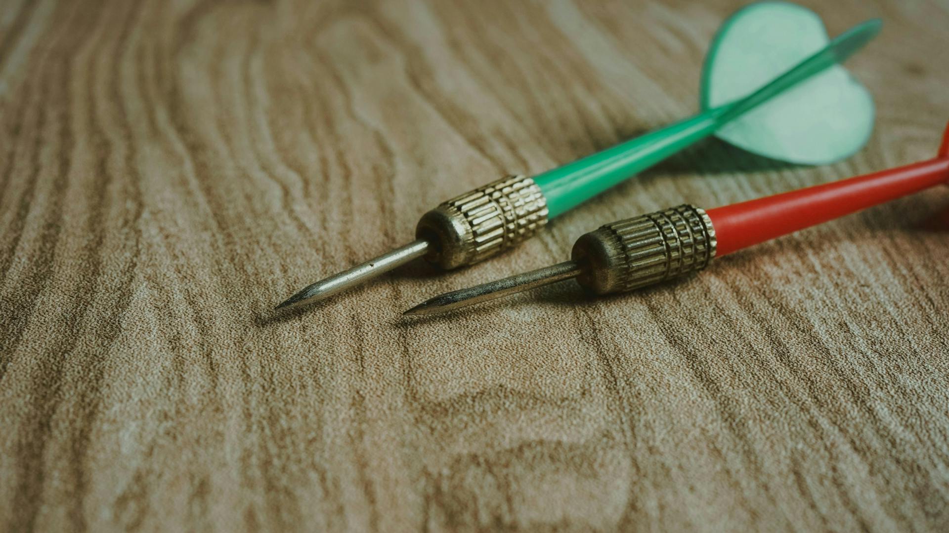 Close up of two different colored darts on a table