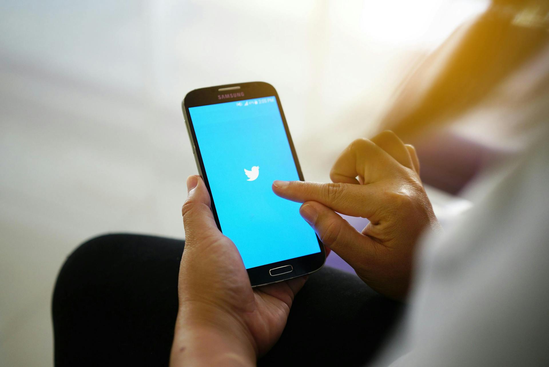 Man sieht, wie jemand auf seinem Smartphone die Twitter App öffnet, weil der weiße vogel auf dem blauen Hintergrund zu sehen ist. Das Foto leitet den Paragraphen zu Twitter Bildgrößen 2022 ein.