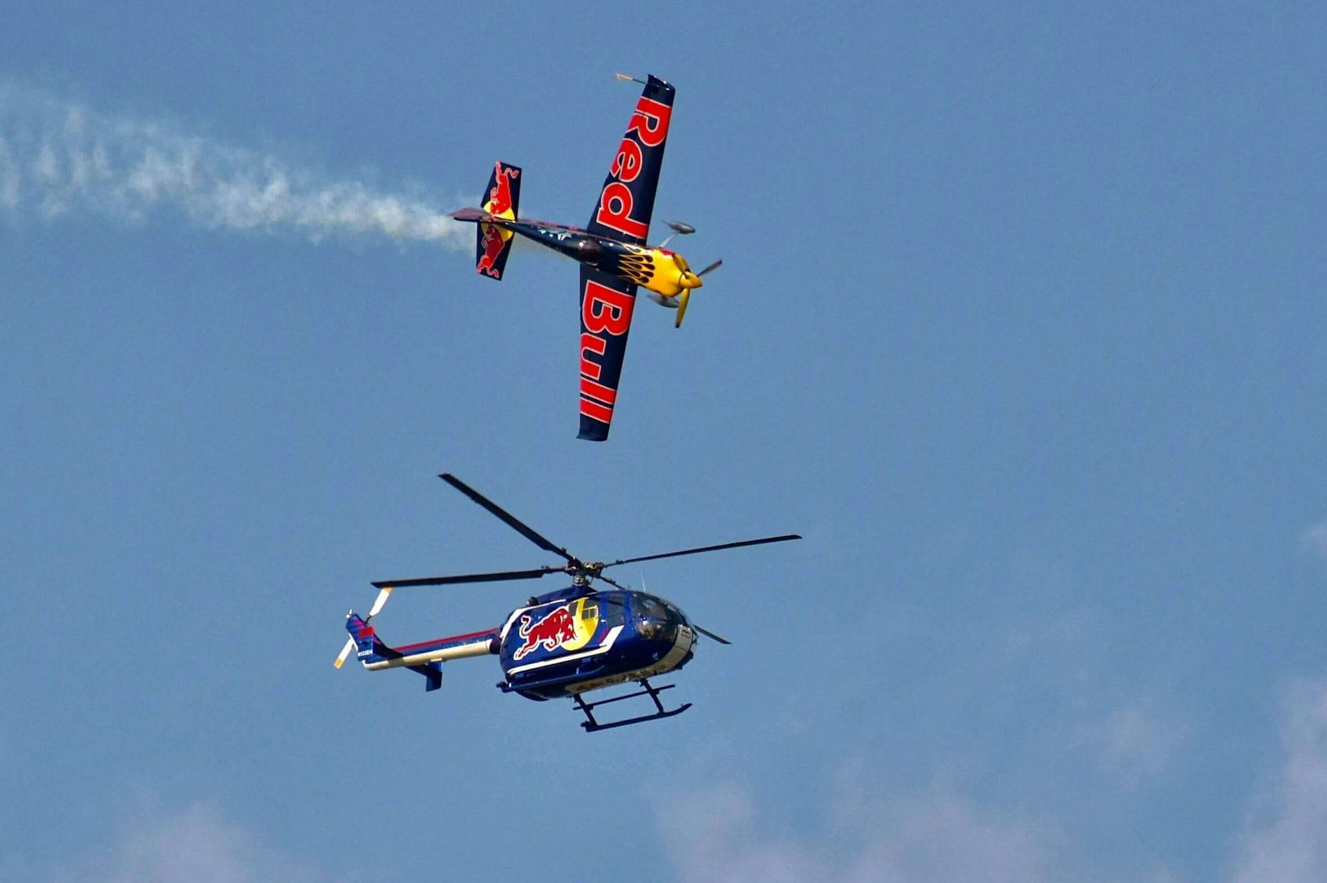 Een afbeelding van een helikopter en een vlietuig van RedBull. RedBull staat erom bekend om vaak extreme evenementen te sponsoren, zoals vliegsporten en skiën vanaf hele hoge bergen. Dit is een voorbeeld van gesponsorde branded content.