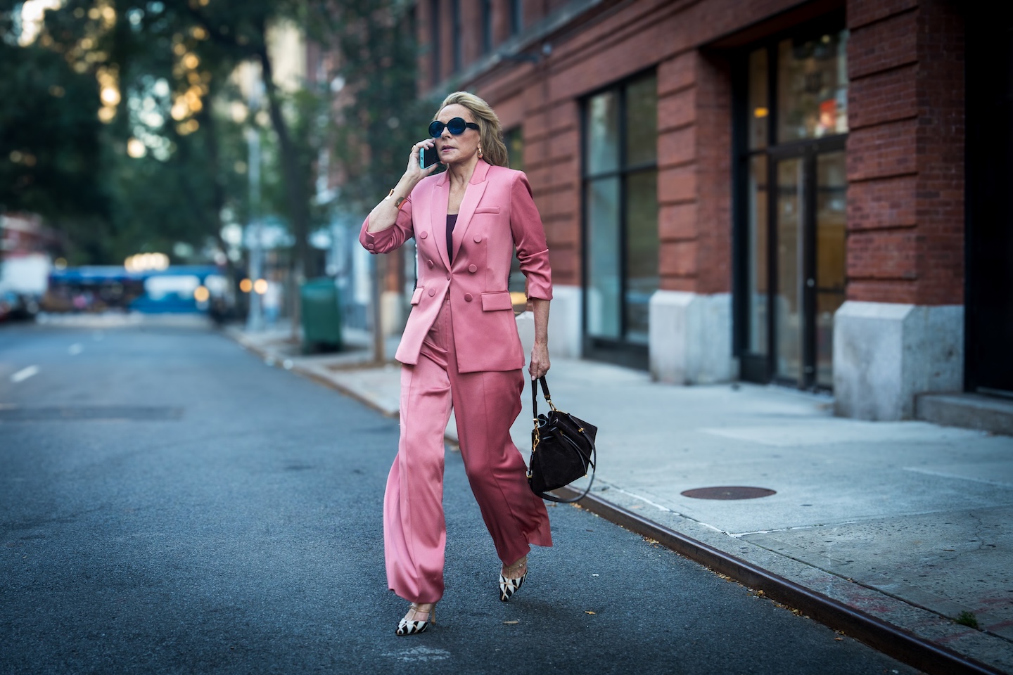 A woman in a pink suit walking along a city street